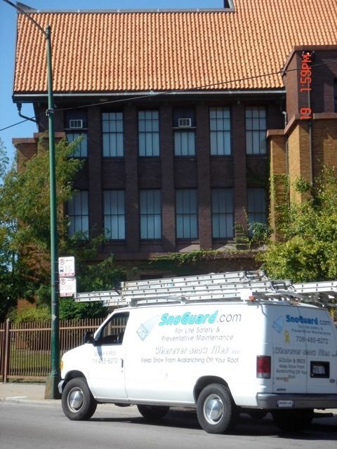 White service van parked in front of a brick building with a red tiled roof.