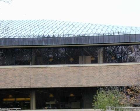 Modern building facade with a curved glass roof and beige brick walls.