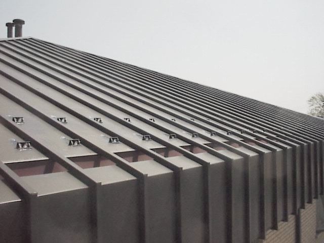 Exterior of a modern building with dark horizontal slats and a cloudy sky above
