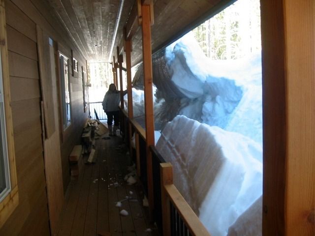 Narrow porch beside a huge snowbank, with a person standing near the far end.