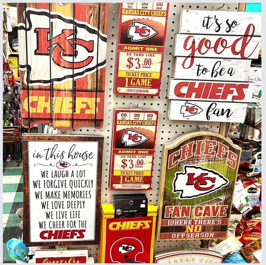 A display of Kansas City Chiefs sports merchandise, including various wooden wall signs, on a white pegboard wall.