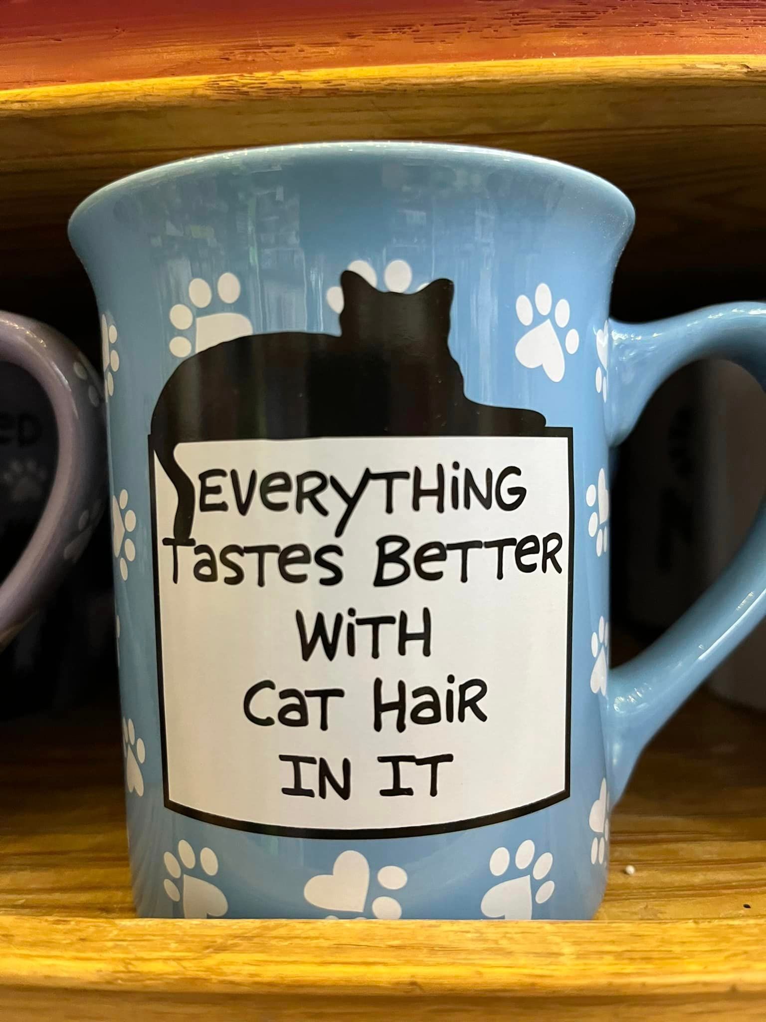 A light blue mug featuring a black cat silhouette and the text:
