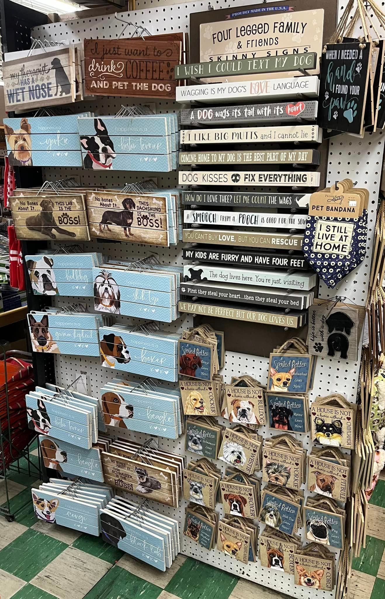 A store display wall featuring assorted wooden dog-themed signs and decor items in various shapes, colors, and sizes.