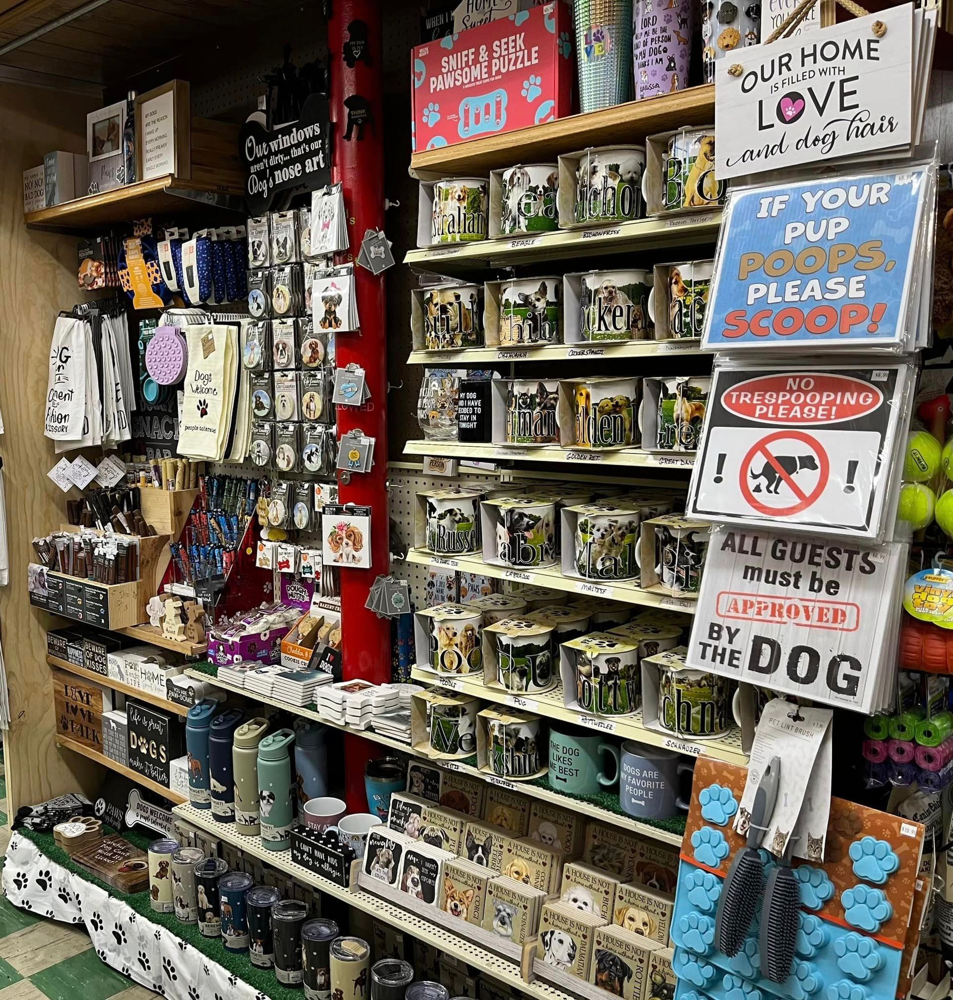 A shop shelf displays various pet-themed merchandise, including mugs, signs with slogans about dogs, and paw-shaped items.