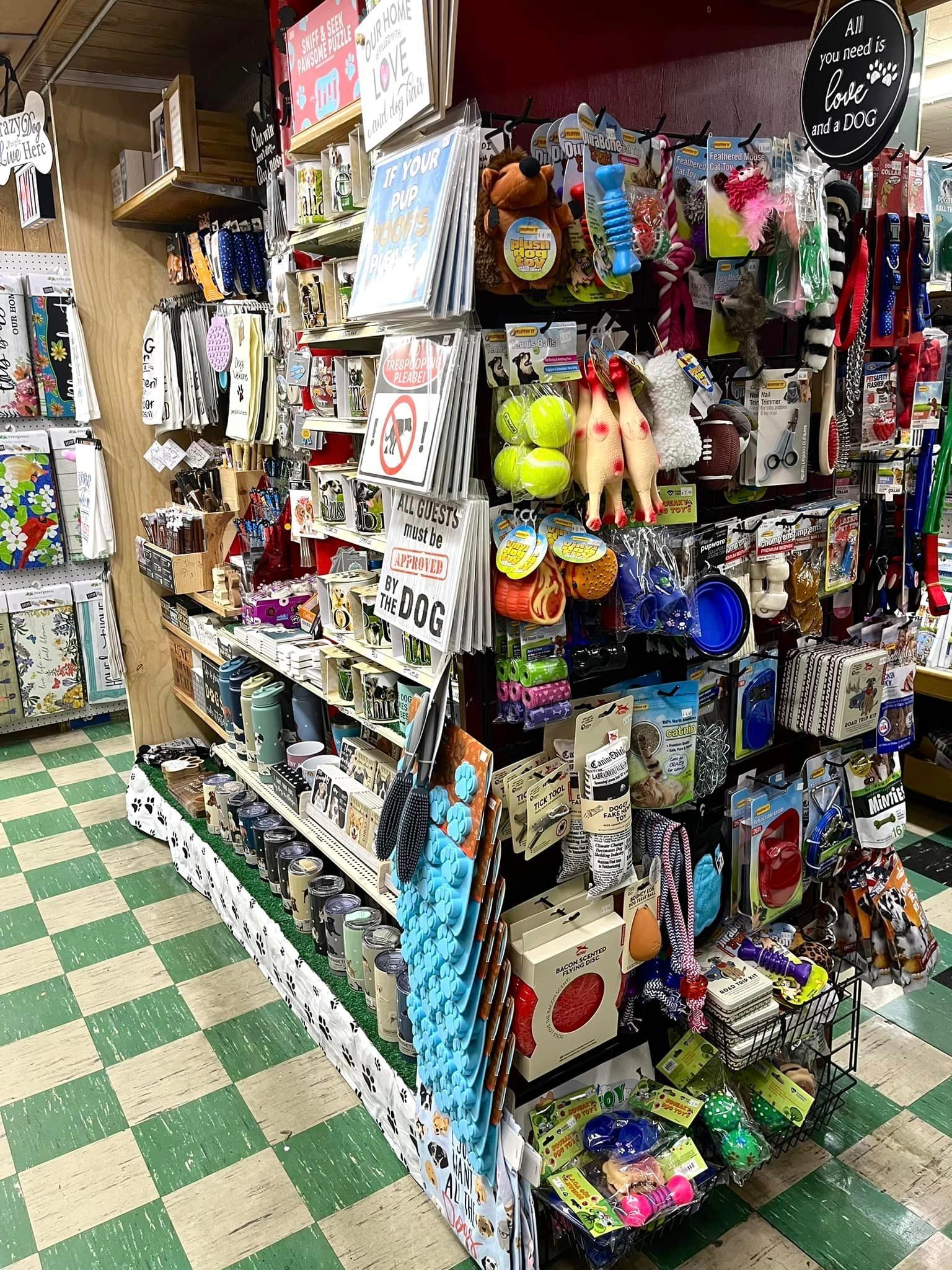 A retail display shelf filled with various small pet supplies, toys, and accessories in a shop with checkered floors.
