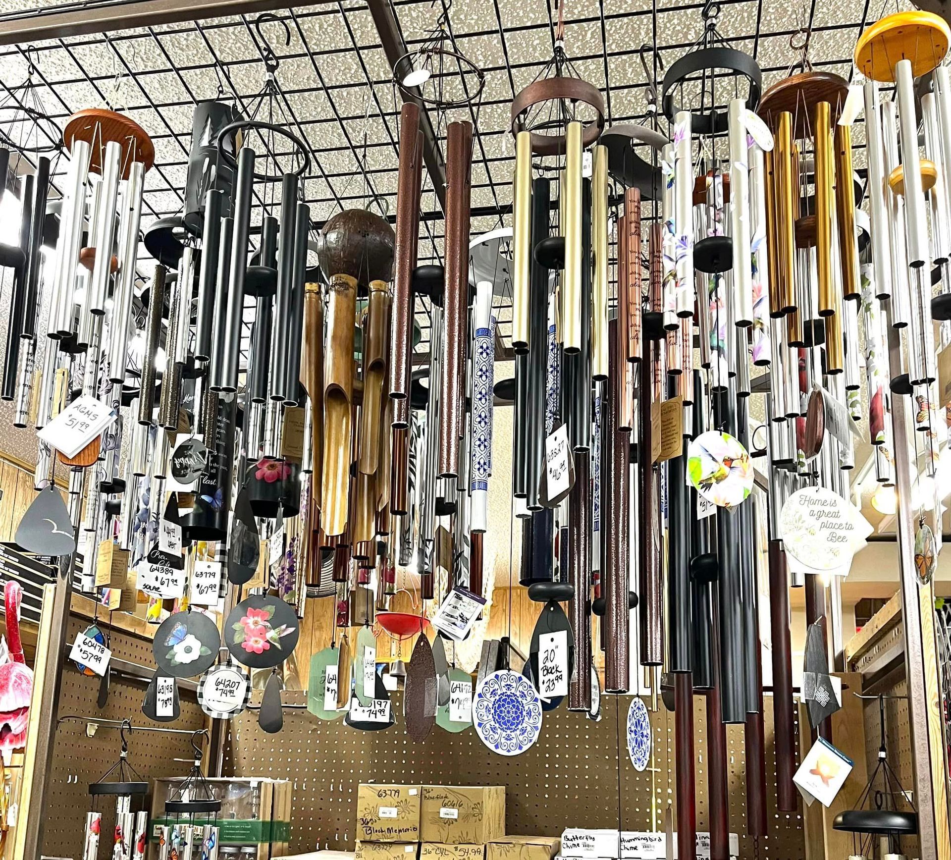 A large collection of various wind chimes, including metal and bamboo designs, hanging from a store display rack.