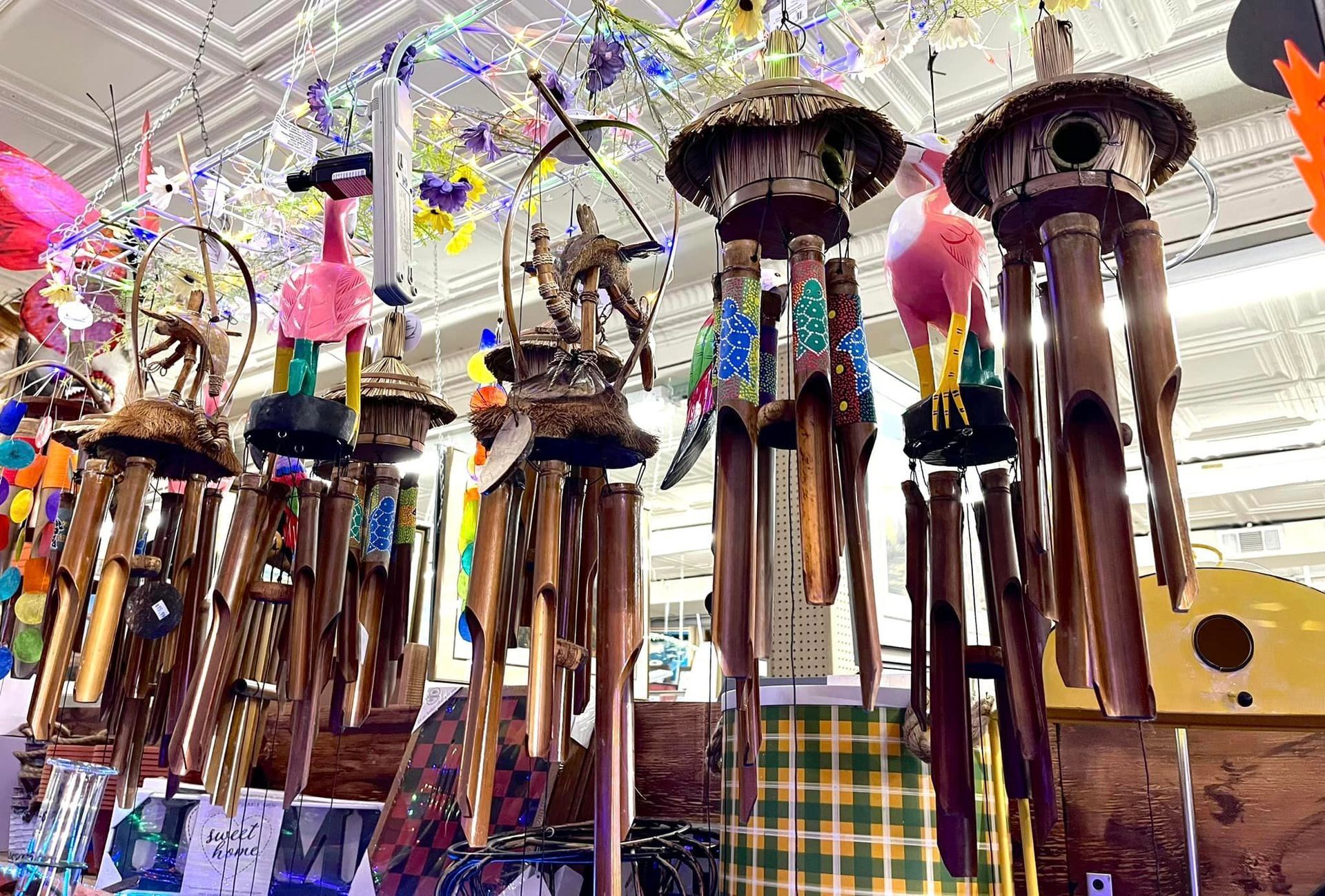 Several decorative bamboo wind chimes with colorful animal figures hanging in a shop.