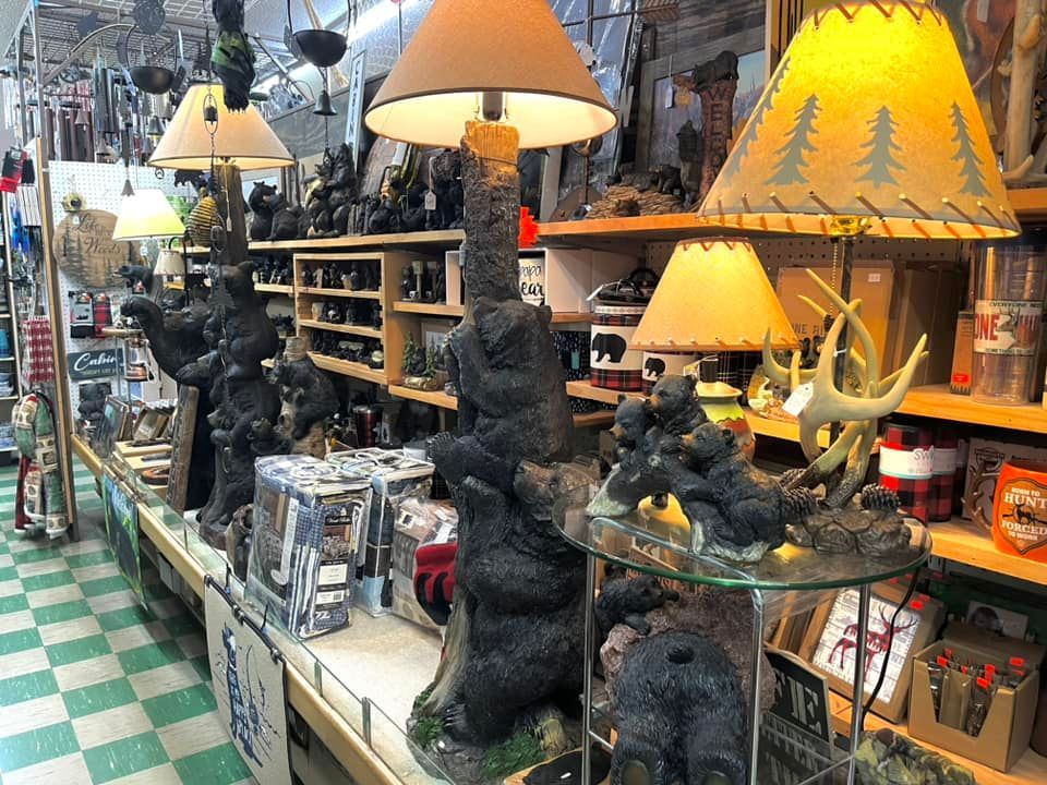 Display shelves in a shop feature rustic bear-themed lamps, decor, and gift items with a checkered floor.