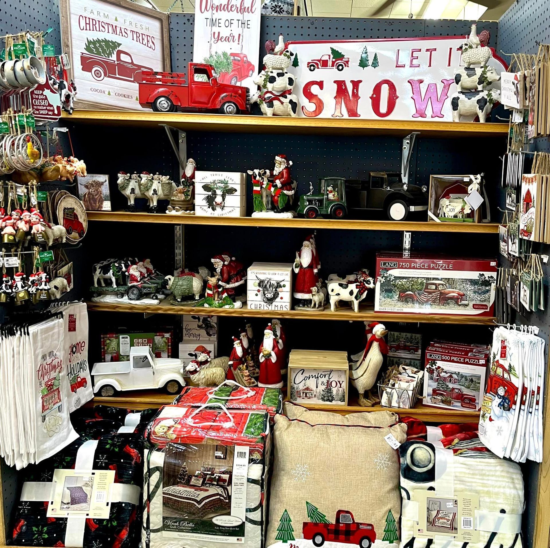 Store shelves filled with assorted Christmas decorations, including signs, figurines, trucks, and festive home textiles.