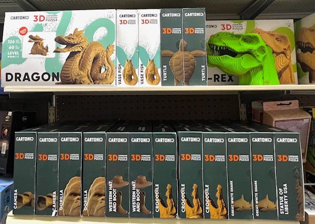 Shelves filled with various 3D puzzle kits featuring animals, objects, and landmarks like a dragon, T-Rex, and gorilla.