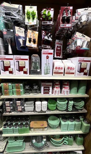 Shelves stocked with retro-style kitchenware, including Coca-Cola branded items, green mixing bowls, and canisters.