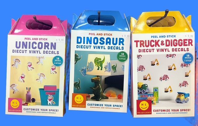 Three boxes of peel-and-stick vinyl wall decals: pink Unicorn, blue Dinosaur, and yellow Truck & Digger themes.