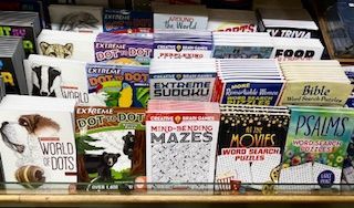 A display shelf filled with various activity books, including dot-to-dots, mazes, and word search puzzles.