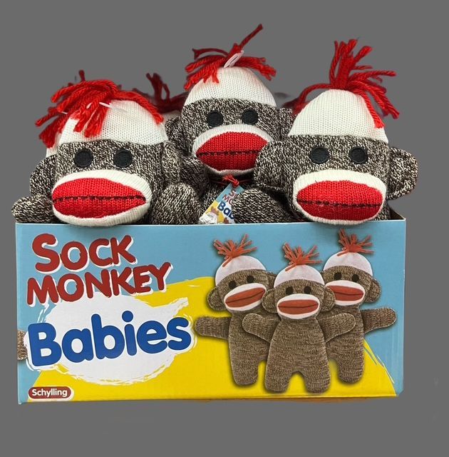 A retail display box of three plush sock monkey toys with red and white knit heads and grey bodies.