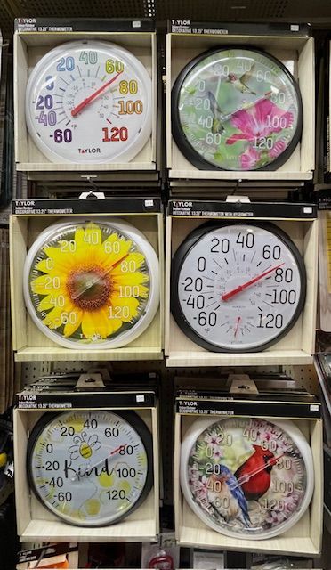 Six outdoor analog thermometers displayed in store packaging, featuring various floral, bird, and simple designs.