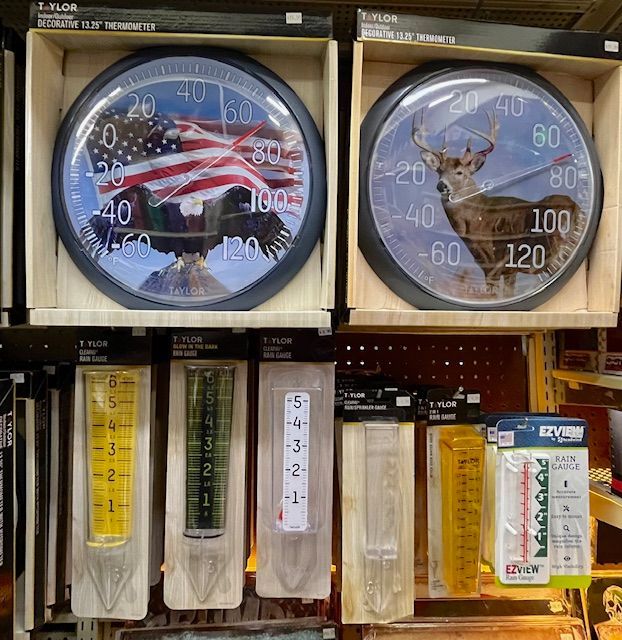Retail store shelves displaying various outdoor thermometers and rain gauges with patriotic and wildlife designs.