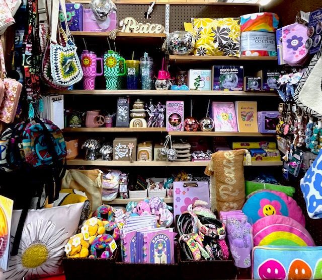 A store shelf display filled with colorful, retro-style decor, accessories, peace sign items, and plush toys.