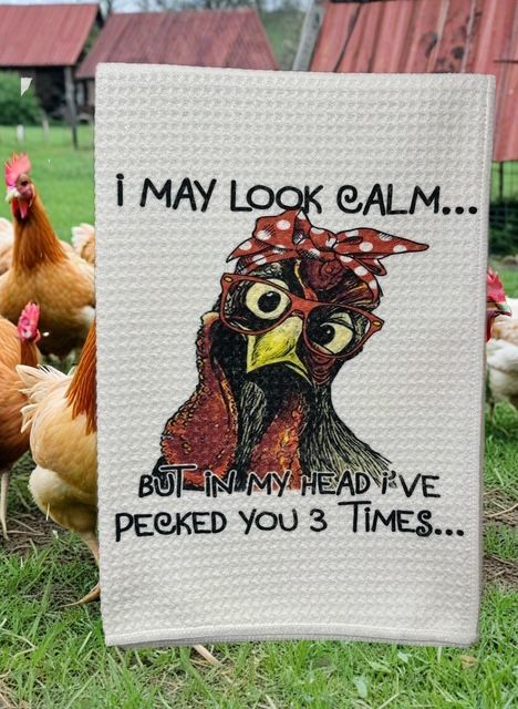 A dish towel held in a chicken coop, featuring a cartoon chicken in glasses and a headband with the text 