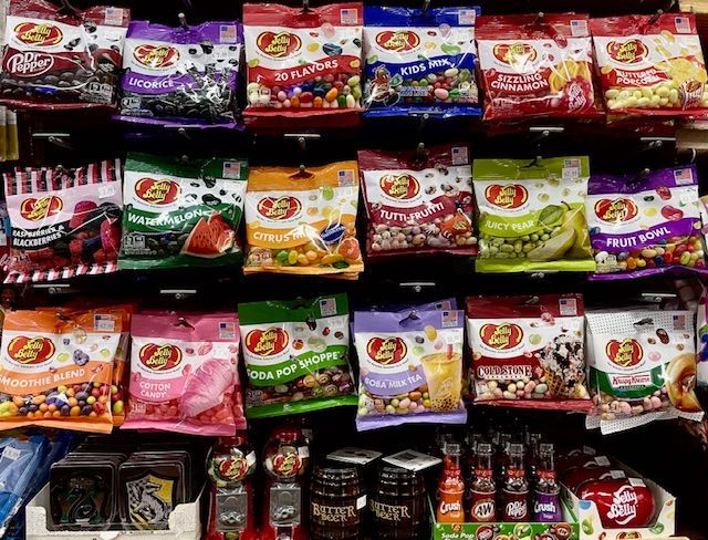 Shelves stocked with many colorful bags of Jelly Belly candy, including various flavors and themed gift boxes.