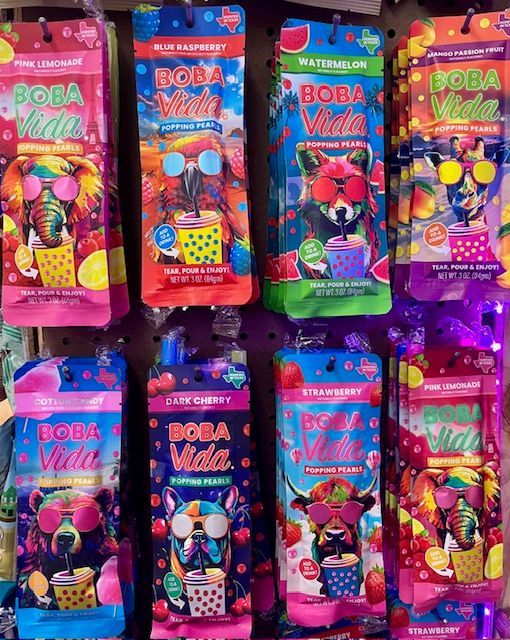 A store display featuring two rows of colorful, illustrated Boba Vida popping pearls pouches with animal characters.