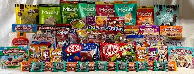 A large assortment of colorful Japanese snacks, including various flavors of Mochi, KitKats, and assorted candies.