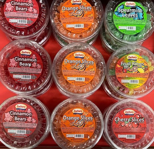 A display of nine plastic containers of Zachary brand fruit-flavored gummy candies arranged in three rows.