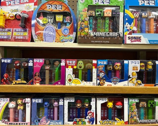 A retail store shelf displaying various packaged PEZ candy dispensers featuring popular character themes.