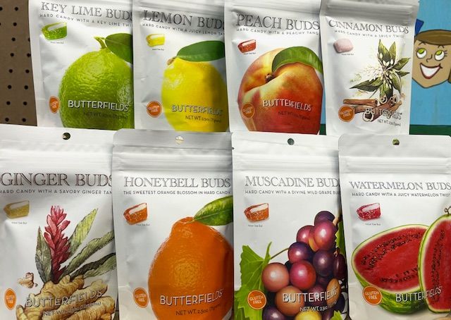 Eight colorful, branded bags of fruit-flavored hard candies arranged in two rows on a shelf.