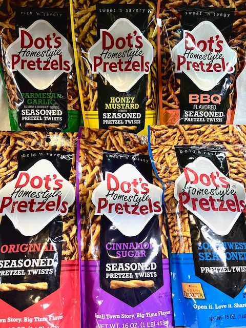 Six bags of Dot's Homestyle Pretzels in various flavors arranged in two rows on a store shelf.