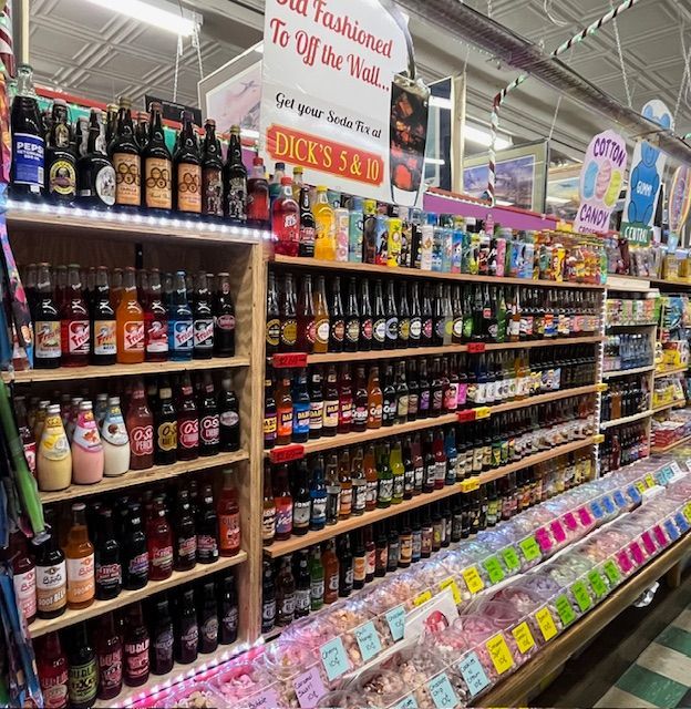 Shelves filled with various glass-bottled sodas and bins of colorful candies at Dick's 5 & 10 store.