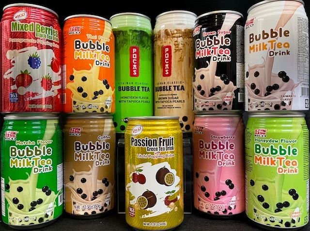 A collection of ten colorful cans of various flavored bubble milk tea arranged in two rows against a black background.
