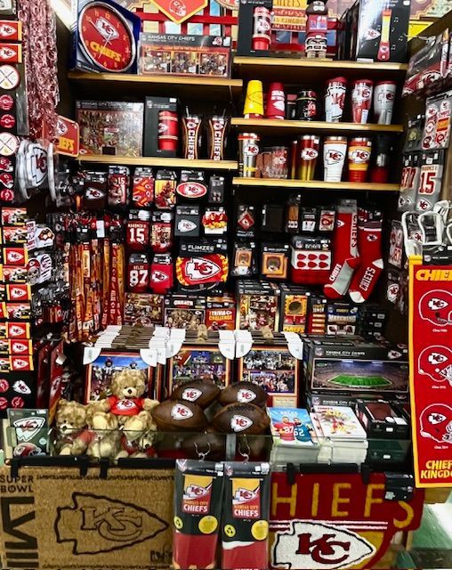 A retail display stocked with Kansas City Chiefs branded merchandise, including apparel, drinkware, and sports memorabilia.