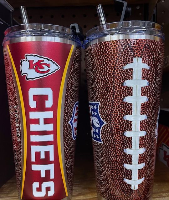 Two Kansas City Chiefs football tumblers with a red and brown textured design, sitting on a retail shelf.