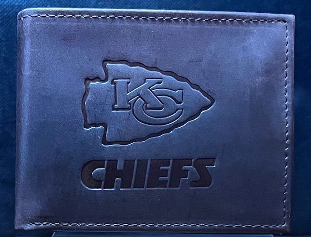 A dark brown leather bifold wallet embossed with the Kansas City Chiefs arrowhead logo and team name.