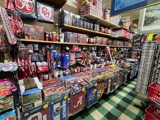 Shelves filled with various university and sports team-themed merchandise, including flags, mugs, and boxed items.