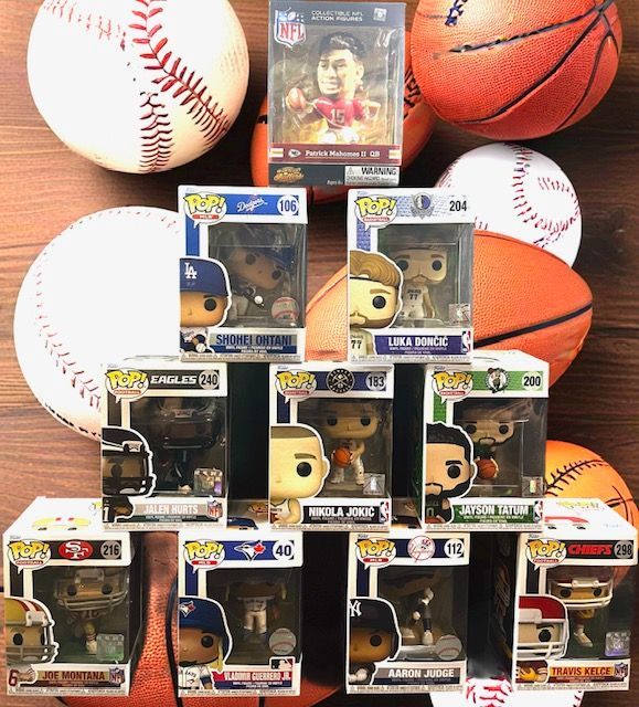 A collection of Funko Pop sports figures in boxes, arranged in a pyramid on top of various baseballs and basketballs.
