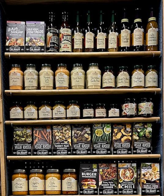 A store display shelf stocked with various bottles of spices, sauces, and culinary seasoning packets.