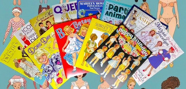 A fan-shaped arrangement of various paper doll books on a blue background patterned with illustrations of paper dolls.