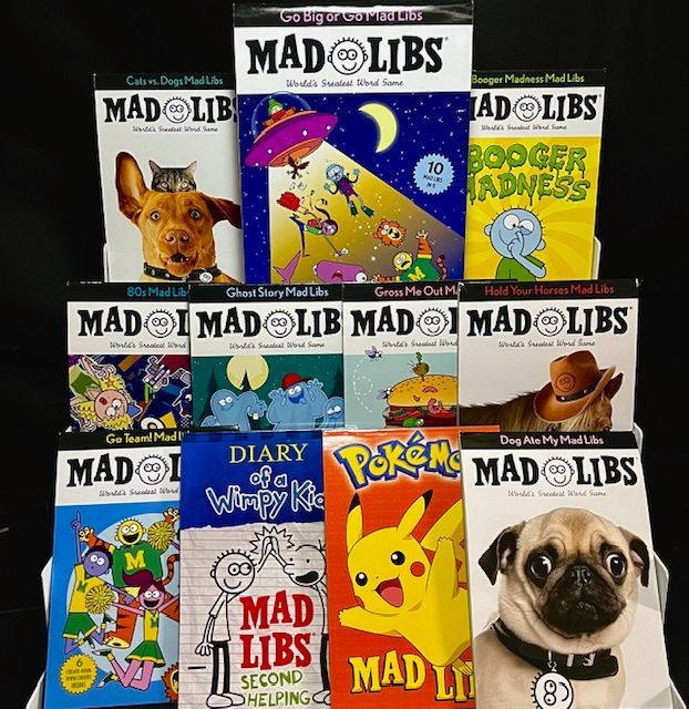 A display rack holding eleven colorful Mad Libs activity books arranged on three shelves against a black background.