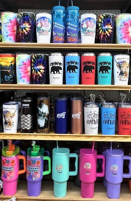 Shelves filled with various colorful travel tumblers and insulated cups in a store.