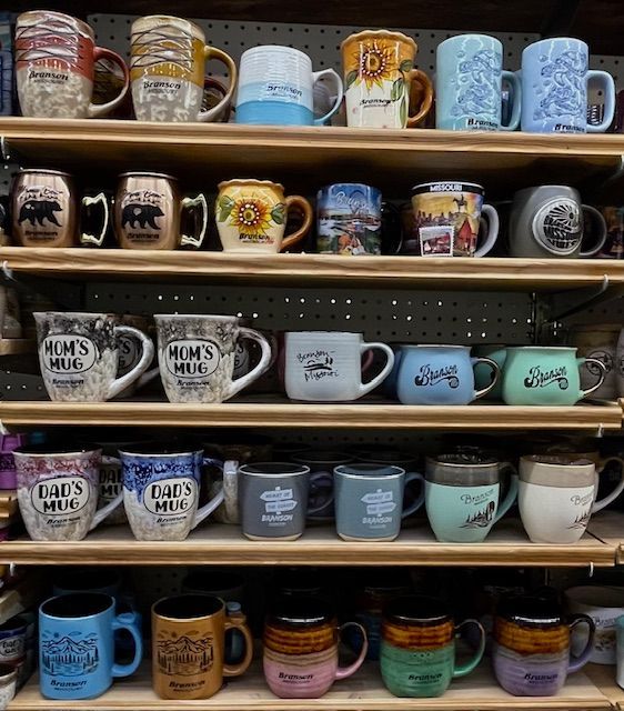 Shelves in a retail store displaying an assortment of ceramic mugs in various colors, designs, and styles.