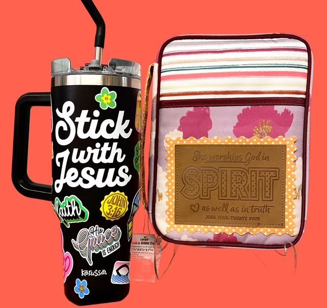 A black tumbler with religious stickers next to a lunch bag with a floral pattern and a patch reading 