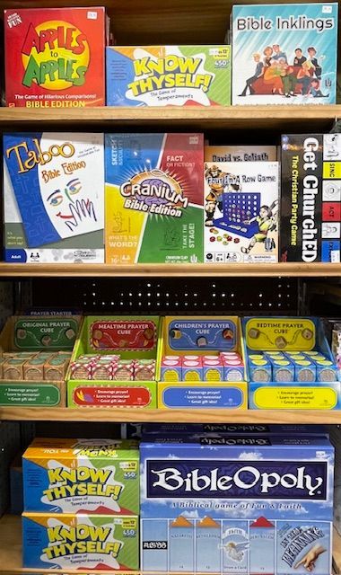 Shelves filled with various Christian-themed board games, including Bible versions of Taboo, Cranium, and Monopoly.