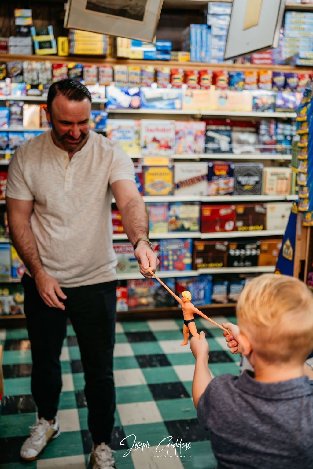 A person and a child stand in a store aisle, playfully stretching a toy figure between them.