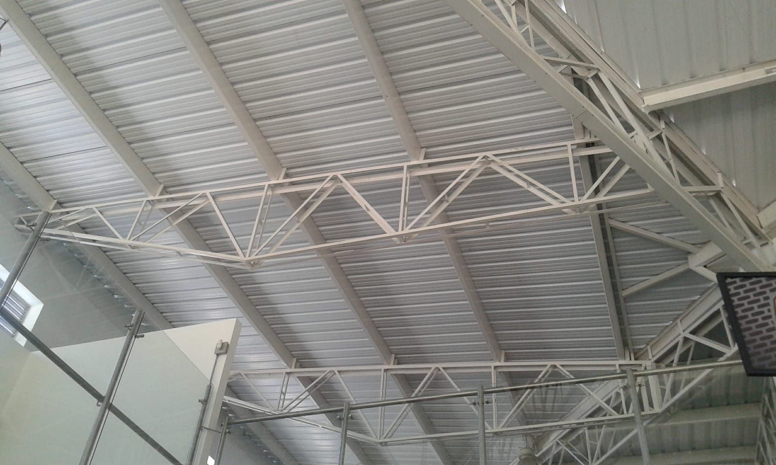 Estructura de cubierta de celosía metálica blanca con paneles de metal corrugado.