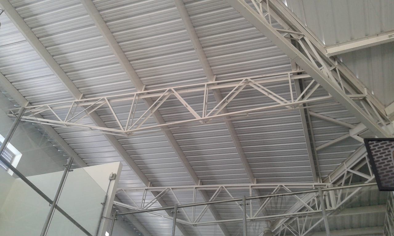 Cubierta metálica blanca con vigas de soporte en nave industrial.