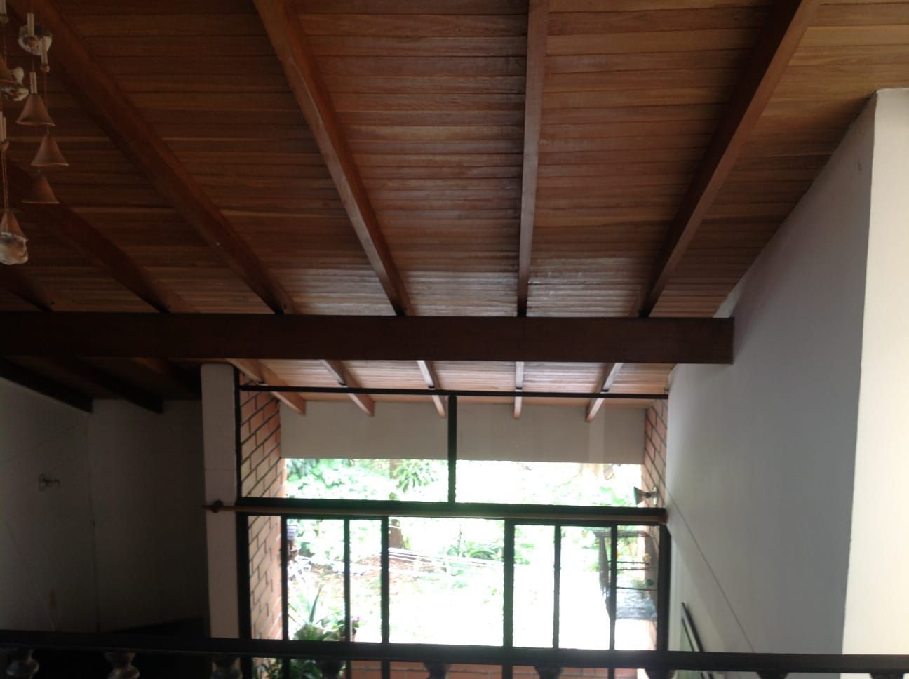 Techo y vigas de madera sobre una puerta de vidrio a un espacio exterior; vista interior.
