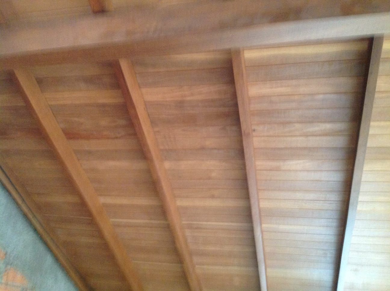 Techo de madera con vigas y tablones vistos.