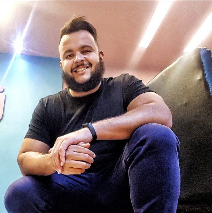 Um homem com barba está sentado em um sofá e sorrindo
