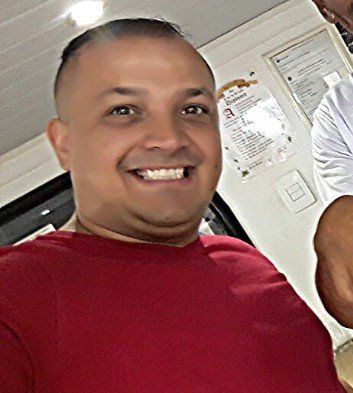 Um homem de camisa vermelha está sorrindo para a câmera